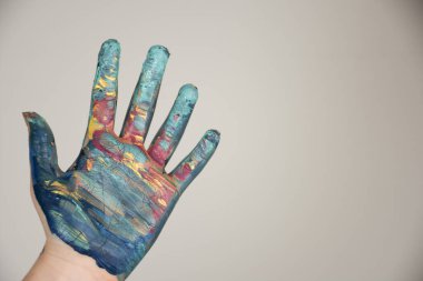 Bej ve kremsi bir arka planda renkli boyanmış bir el.