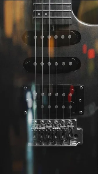 Czerwony Błyszczący Gitara Elektryczna Stojąca Pionowo Czarnym Bokeh Teksturowane Tło — Zdjęcie stockowe