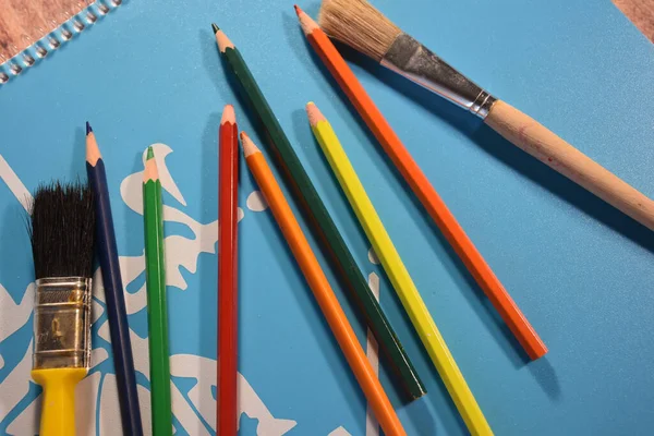 在蓝色背景上分离出各种彩色铅笔和画笔 — 图库照片