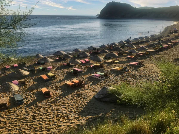 Gökceada Laz körfezi kıyı manzarası, kumdaki güneş panoları ve renkli deniz şemsiyeleri. 08.28.2021 Gkeada, Türkiye. Imbros Adası