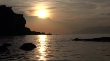 Issız bir sahilde gün batımı ve sakince dalgalar. 4K