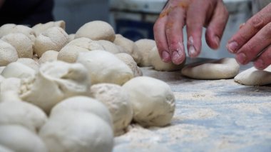 Erkek aşçı mutfakta elleriyle hamur topları hazırlıyor.