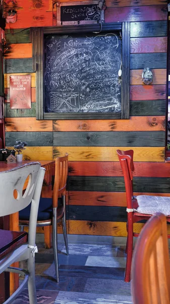 背景には木製のデザインのヴィンテージ木製の壁 壁には黒板 その前には空の木製のテーブルと椅子 — ストック写真