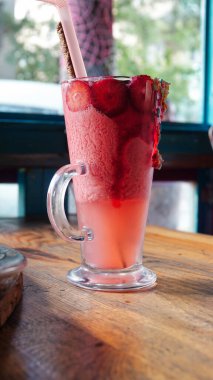 Bir bardak pembe çilekli milkshake ezilmiş buz, meyve, çikolata sosu ve şeker parçacıklarıyla servis edilir. Çilekli smoothie.