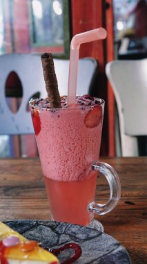 Bir bardak pembe çilekli milkshake ezilmiş buz, meyve, çikolata sosu ve şeker parçacıklarıyla servis edilir. Çilekli smoothie.