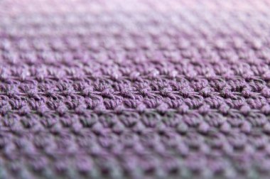 Yumuşak odaklanma ve seçici odaklanma. Çok renkli ipliklerden örgü örme ürünü. El yapımı arka plan. Mor bir baktüs parçası mı yoksa çok peri ve gri bir ton mu? Çizgili ve geometrik desen