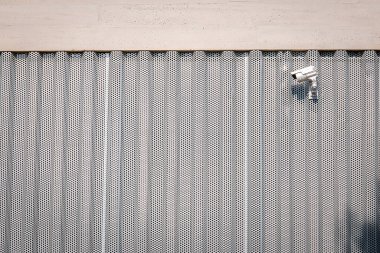 Metal ve beton bir binanın üstüne monte edilmiş güvenlik kamerası..