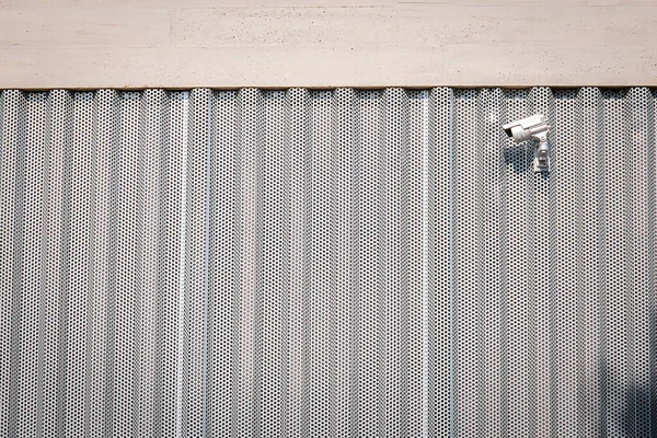 Metal ve beton bir binanın üstüne monte edilmiş güvenlik kamerası..