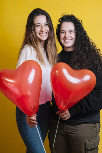 Pareja Dos Chicas Posando Con Globos Cardíacos Sobre Fondo Amarillo —  Fotos de Stock