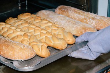Baker fırından somun ekmeği eldivenle çıkarıyor..
