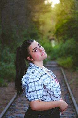 Terk edilmiş tren raylarında duran bir genç..