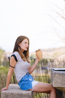 Girl pausing and having coffee outdoors.