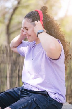 Brunette girl with curly hair listening to music.