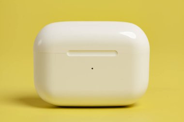 Sarı arka planda şarj çantasındaki kablosuz kulaklıklar.