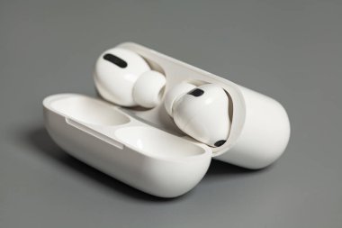 Gri arka planda şarj edilen kablosuz kulaklık..