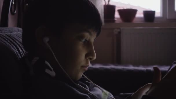 テレビゲーム中毒の少年が暗室でタブレットで遊んでいます — ストック動画