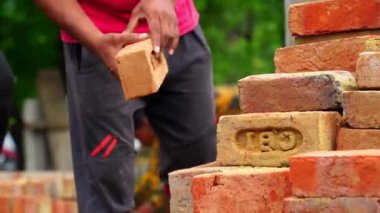 Kırmızı tuğlalı Hintli işçiler dışarıda. Hintli inşaat işçileri Jaipur yakınlarında traktörden tuğla indiriyorlar.