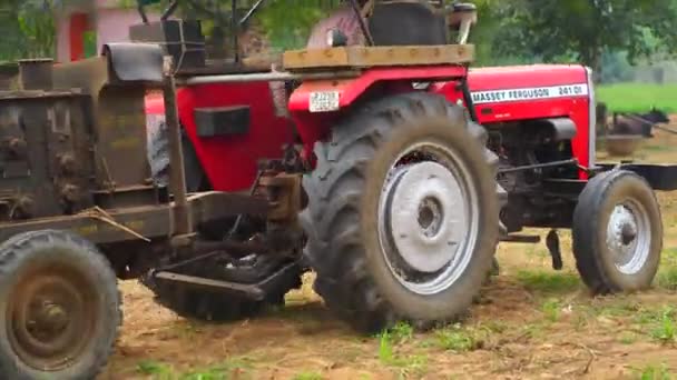 После стрижки травы "Красный трактор" едет по пустому полю с молотилкой. — стоковое видео