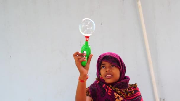 Imágenes de 4k, niña india está jugando pistola de burbujas en el patio trasero. Chica disfrutando por la mañana. — Vídeos de Stock