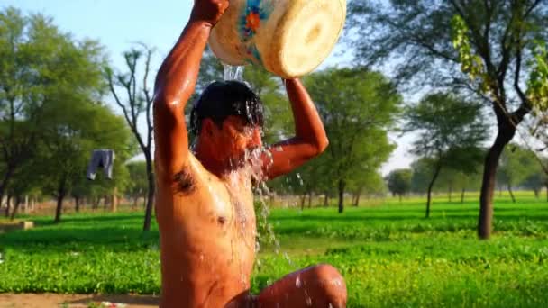 A Indian man pours water from a bucket. Indian rural footage concept. — Stock Video