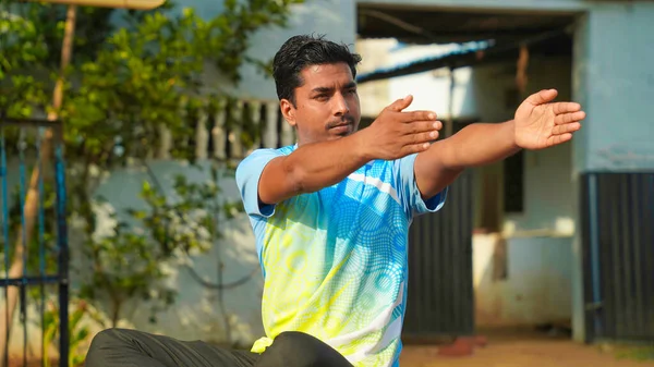 Good looking man in blue sport shirt and black pants sitting on yoga mat doing maditation with hand