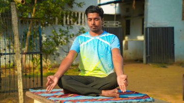 Rahatlamış genç adam yoga yapıyor ve dışarıda meditasyon yapıyor..