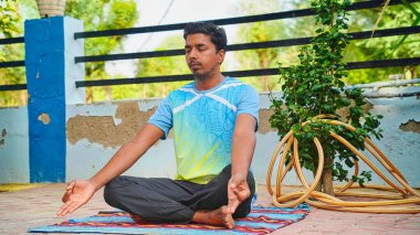 Yoga pozisyonunda oturan çekici genç Hintli adam. Her sabah yoga çalışıyorum..