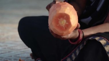 Hintli kadın papaya ve portakallı smoothie yapıyor. Papayayı soyuyordum. 4k Merkez Videosu