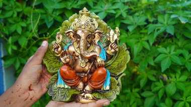 Eco friendly Ganesh or Ganpati idol or murti in hand with nature background, home made. selective focus. Ganesha chaturthi festival 2022.