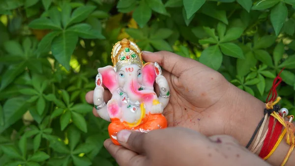Eco friendly Ganesh or Ganpati idol or murti in hand with nature background, home made. selective focus. Ganesha chaturthi festival 2022.