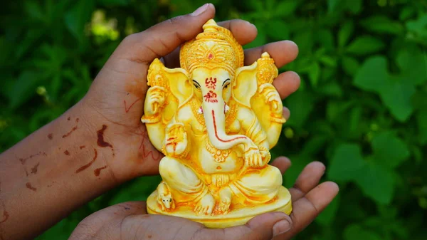 Eco friendly Ganesh or Ganpati idol or murti in hand with nature background, home made. selective focus. Ganesha chaturthi festival 2022.