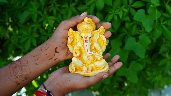 Lord Ganesha idol in hand, Golden lord ganesha sculpture on nature background. Celebrate lord ganesha festival 2022.