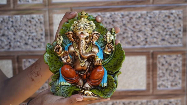 Eco friendly Ganesh or Ganpati idol or murti in hand with blur background, home made. selective focus. Ganesha chaturthi festival 2022.