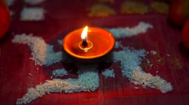 Çok renkli pirinç taneleri ve seçici odak noktasıyla Rangoli 'nin üzerine yerleştirilmiş Diya ya da kil yağı lambası kullanarak güzel Diwali selamı.