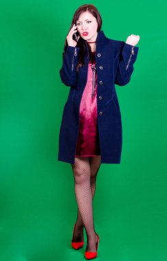 Bir kadın telefonda konuşuyor ve yeşil arka planda kızgın.