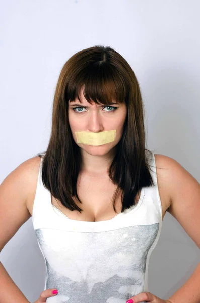 Young woman with taped mouth