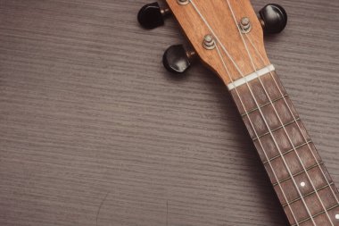 Ukulele yakından bakınca, dört telli klavyeyi görebilirsiniz. Ahşap arkaplan.