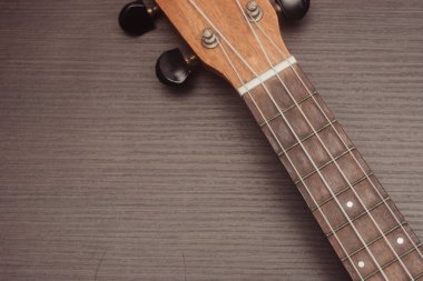 Ukulele yakından bakınca, dört naylon telli klavyeyi görebilirsiniz. Taşınabilir telli alet. Ahşap arkaplan