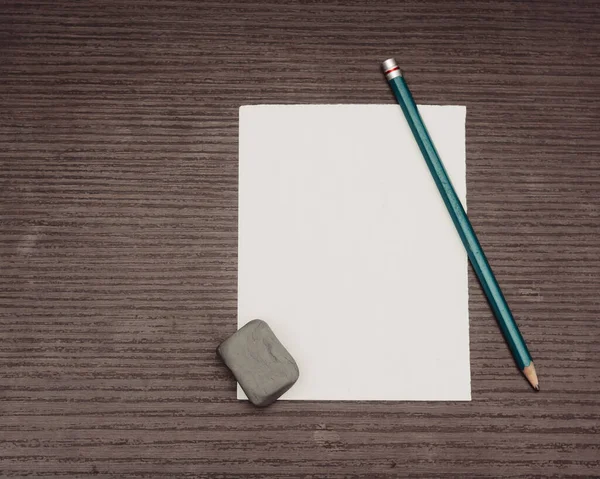 blank paper with pencil and pen on wooden background