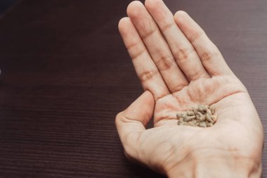 Tahta bir arka planda bir avuç buğday tohumunu tutan el.