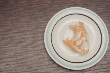 Fıstık ezmeli bir kaşık ekmek ve konsantre süt ile bir fincan kahvenin olduğu beyaz bir tabağın mutfak fotoğrafı. Isır.