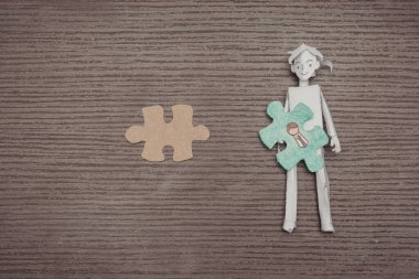 Ahşap bir arka planda çalışan bir kağıt işçisiyle yapboz parçaları. İş konsepti