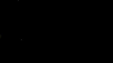 4k Parlak ışık ve etrafa saçılmış altın parçacıkları siyah bir arkaplan üzerinde.