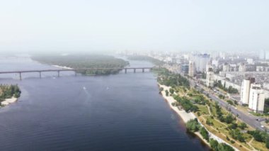 Büyük şehir manzarası, nehir kıyısında yol boyunca giden gökdelenler ve arabalar.