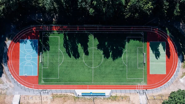 Koşu pistleri ve kortlarıyla geniş doğal yeşil bir futbol sahasının en üst görüntüsü