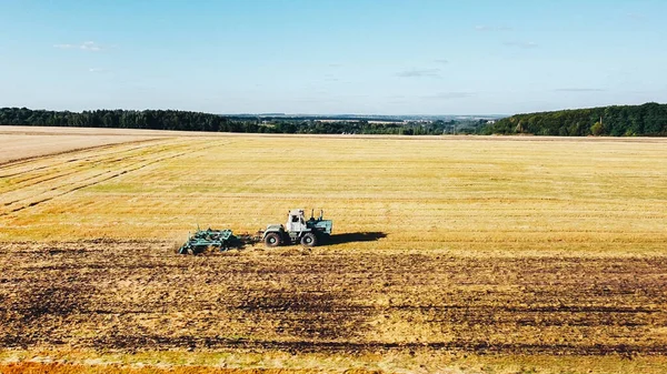 Vista aérea como cosechadora de tractores limpiando un campo de trigo después de la cosecha — Foto de Stock