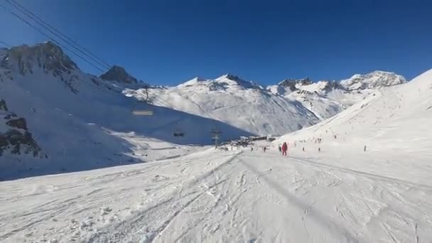 En snowboardåkare stiger i fart från en bergssluttning i Alperna — Stockvideo