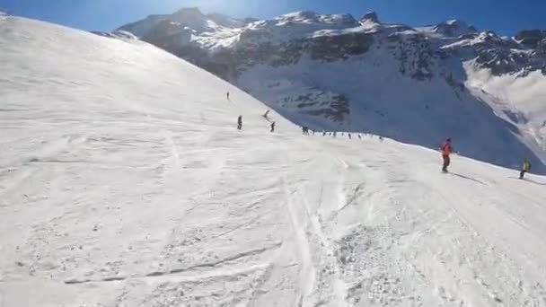 A snowboarder in an orange suit descends a slope — Vídeo de Stock