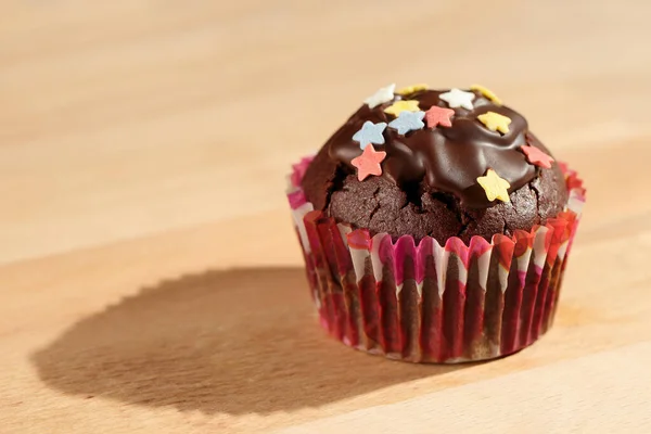Hemlagad Läcker Kakaomuffin Med Färgglada Sockerstjärnor Och Mörk Chokladglasyr Träskiva — Stockfoto