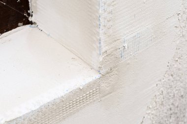 Pencerenin dış köşesinde plastik ağ olan yeni monte edilmiş alçı açı boncukları. Seçici odak